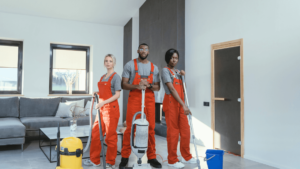 A Group Of People In Overalls Holding Vacuum Cleaners