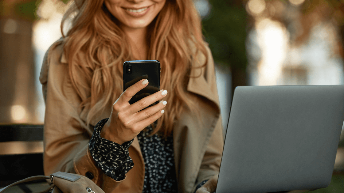 A Woman Holding A Phone And Looking At Her Laptop Https://Websitedesignstlouis.com