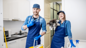 Commercial Cleaners In Blue Overalls And Hats Holding Dusters And A Bucket